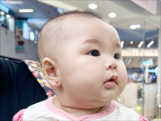 Baby receiving her first safe and gentle ear piercing at Stellar Malaysia.