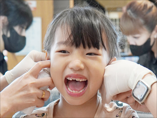 Young girl happily getting her ears pierced at Stellar Malaysia, a trusted ear piercing service